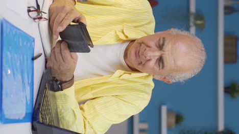 Vertical-video-of-Home-office-worker-old-man-showing-his-empty-wallet-to-the-camera.